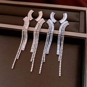 Close-up of geometric tassel earrings with zircon in rose gold and silver finishes