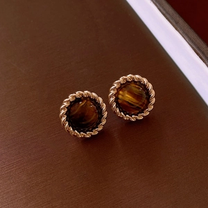 Close-up of vintage round tiger eye earrings with a twisted gold-tone metal border