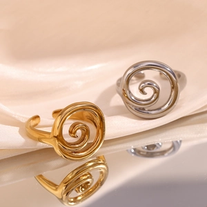 Detail of gold and silver spiral rings on luxury beige silk with mirror reflection