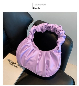 Close-up of purple pleated faux leather handbag on a chic black leather chair
