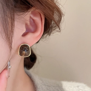 Close-up of a retro amber resin trapezoid earring with gold trim on a model ear