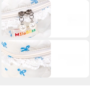 Detailed shot of smooth dual zippers with pearl charms and lace edges on a bow cosmetic bag