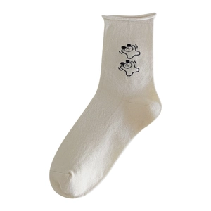 Süße cremeweiße Socken mit schwarzer Cartoon-Hunde-Stickerei auf weißem Hintergrund