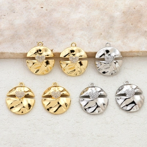 Macro detail of 14k gold-plated hammered round pendants with zircon heart centers