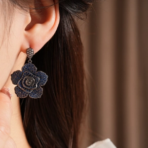 Close-up of vintage navy blue floral earrings with pavé stones on a model's ear