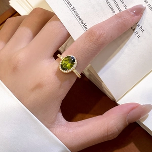 Close-up of 18k gold plated ring featuring oval green zircon stone worn by a model