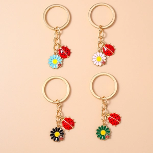 Detail of ladybug and colorful daisy flower keychains with golden metal finish