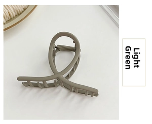 Detail view of a matte light green shark hair claw clip with strong metal spring