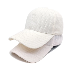 Close-up of beige tweed baseball caps with textured woven fabric and frayed details