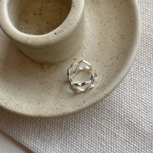 Close-up of minimalist S925 sterling silver hollow heart ear cuff on ceramic plate