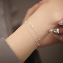 Close-up of minimalist double-layer silver chain bracelet with moonstone heart on wrist