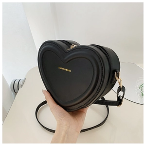 Dettaglio della borsa a tracolla nera a forma di cuore in pelle con cerniera dorata