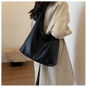 Litchi texture black leather tote bag worn with beige trench coat for a stylish look