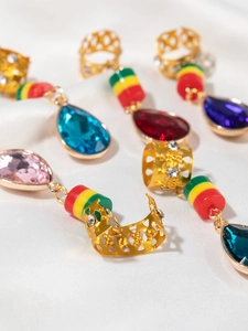 Detail of crystal teardrop charms and gold braided hair accessories on white silk fabric