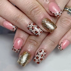 Close-up of short press-on nails with leopard print, gold glitter, and French tips