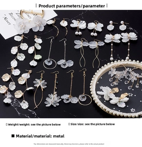 Gros plan de boucles d'oreilles fleurs blanches avec perles et glands dorés sur marbre