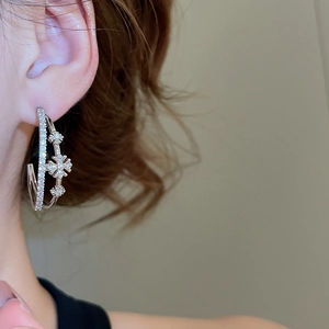 Détail de boucles d'oreilles doubles en C argentées avec fleurs en zircon sur un mannequin