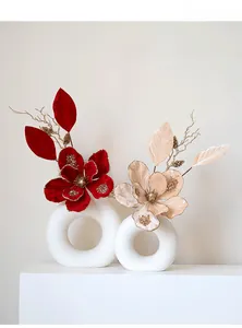 Detail of glittery velvet poinsettia flowers in matte white hollow ceramic vases