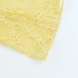 Macro shot of detailed floral lace pattern on yellow off-shoulder bodycon dress