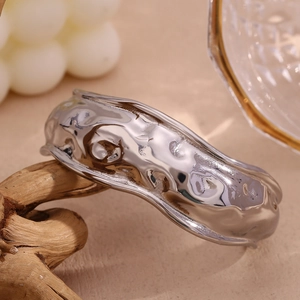 Macro detail of silver-tone irregular lava texture bangle on a wooden stand