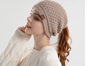Detail of oatmeal knit beanie featuring chunky texture and unique ponytail hole design