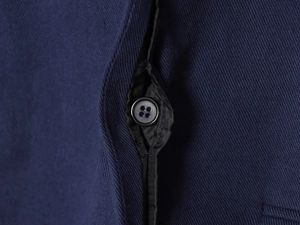 Macro shot of navy twill fabric detail and black four-hole resin button on the placket