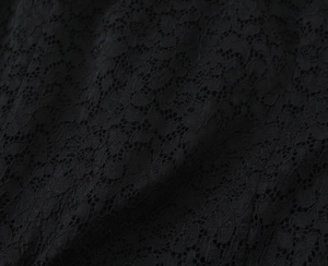 Close-up of intricate black floral lace fabric with delicate hollow-out embroidery detail
