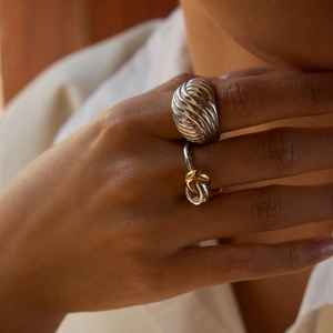 Detailed close-up of a twisted silver and gold ring set on a model's finger