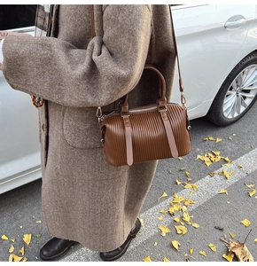 Close-up of vintage brown pleated pillow bag with matte PU leather texture and gold hardware