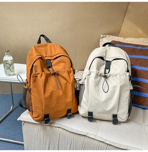 Zwei Rucksäcke in Orange und Off-White aus Nylon mit großem Fassungsvermögen auf Sofa