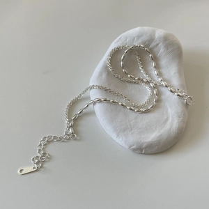 Detail shot of a S925 sterling silver chain necklace on white stones with adjustable clasp