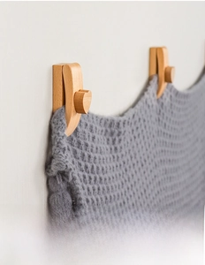 Macro detail of wooden tapestry hangers with heart design holding a gray knit blanket