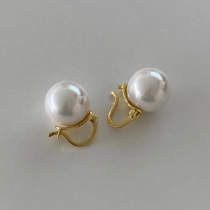 Detail view of 925 sterling silver pearl earrings with polished gold clasps