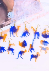 Detail view of silicone animal molds with shimmering resin earrings in starry blue and orange