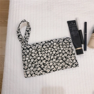 Détail de la mini pochette en tissu à fleurs avec dragonne pour maquillage et accessoires