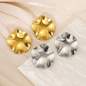 Vue détaillée de boucles d'oreilles rondes ondulées en finitions dorées et argent