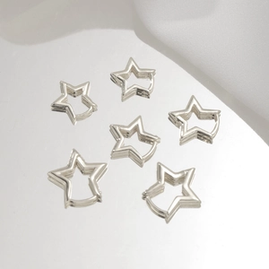 Macro detail of six polished silver star-shaped hoop earrings on a reflective surface
