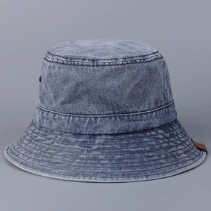 Close-up of washed denim bucket hat featuring reinforced stitching and brown leather label