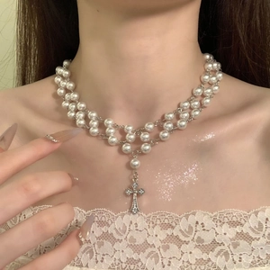Detailed close-up of double-layer pearl choker necklace with zircon cross pendant