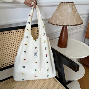 Detailed close-up of white canvas tote bag featuring colorful floral embroidery