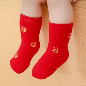 Close-up of red cotton baby socks with yellow Fu character pattern for festivals
