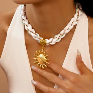 Macro detail of sun pendant with hammered texture on white woven rope necklace