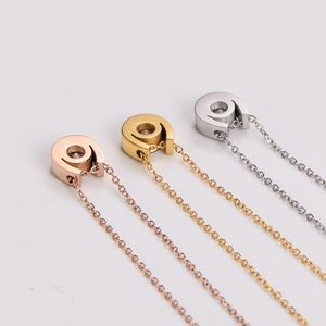 Dettaglio dei ciondoli a forma di U con zirconi cubici in tre colori metallici per collane