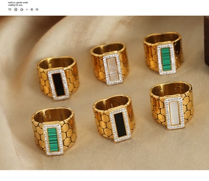 Detailed shot of gold honeycomb rings with emerald, black, and mother of pearl square stones
