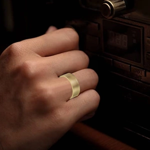 Macro shot of 8mm gold titanium ring with horizontal brushed texture on male hand