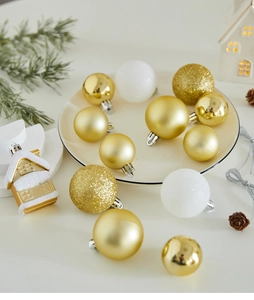 Close-up of gold and white Christmas ornaments with matte and glitter textures on a table