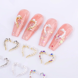 Symmetrical heart nail art charms with pearls and rhinestones on pink glitter nails