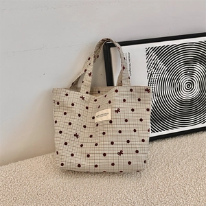 Détail du sac à lunch en toile avec motifs à carreaux rouges et broderies de nœuds