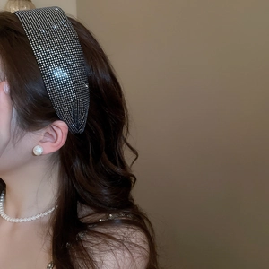 Detail of a wide luxury headband with shimmering black rhinestones on wavy hair