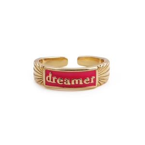 Detail of gold plated ring featuring pink enamel plaque with engraved Dreamer text